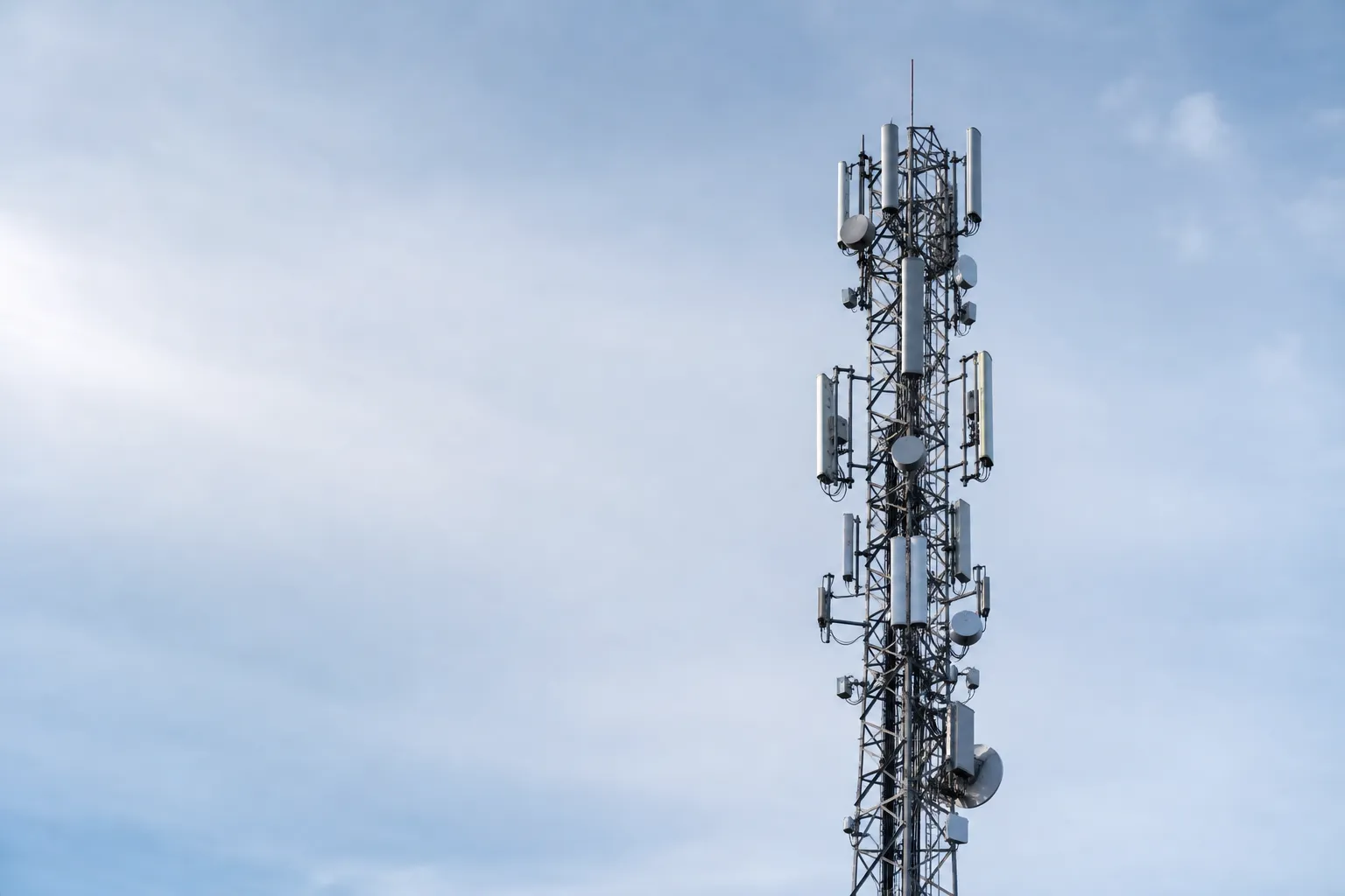 Telekommast med antenner i flera lager mot nordisk himmel